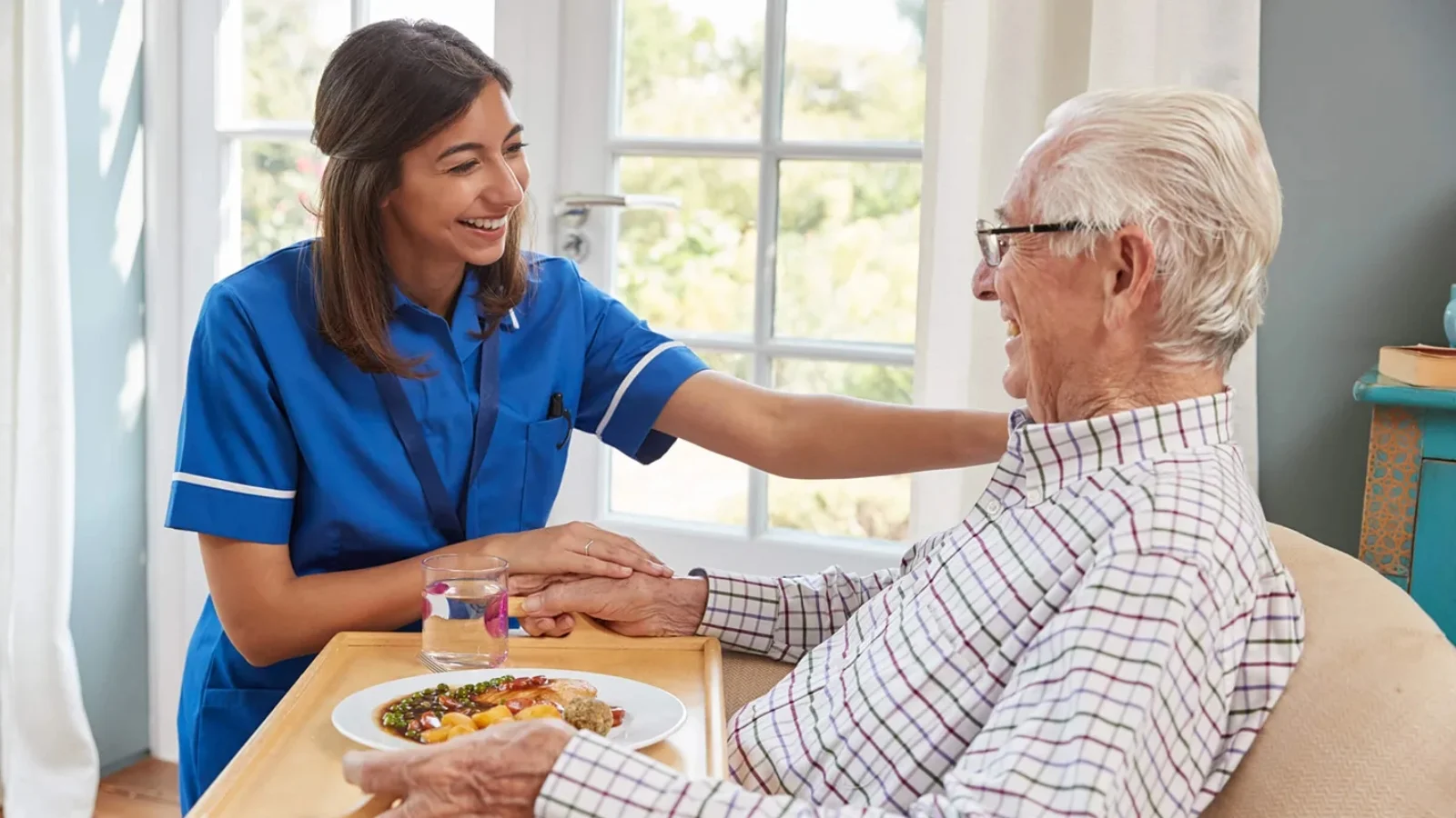 Caregiver holding hand of senior resident at Compassionate Care Senior Living